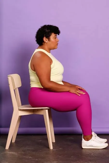 Person seated on a chair in pink leggings against a lilac background