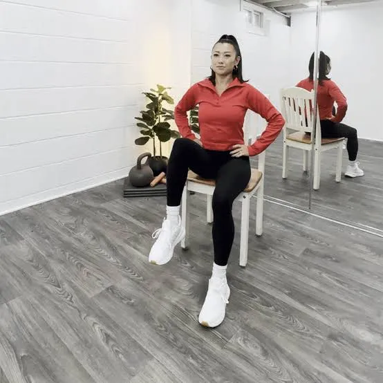 Woman in red doing seated chair exercise in a bright studio