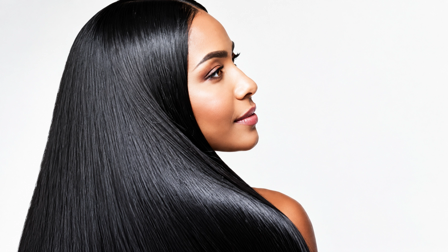 A woman in profile with very long straight black hair flowing over her shoulder against a pale background