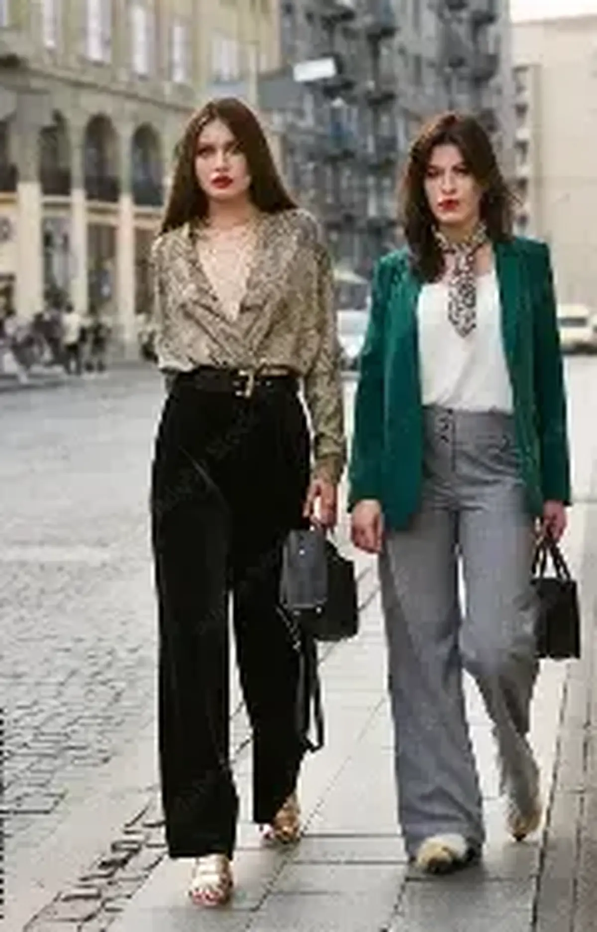 Two women walking a European city street in patterned and green tailoring with bags