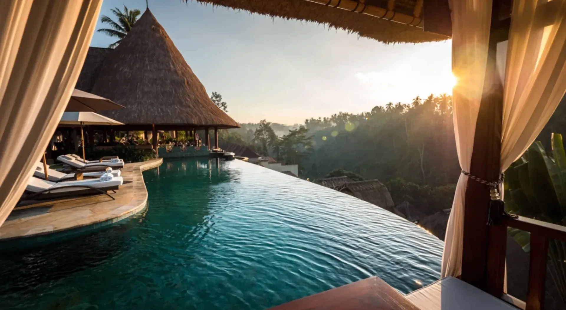 Infinity pool overlooking a jungle valley at sunrise, with a thatched-roof pavilion and loungers beside it
