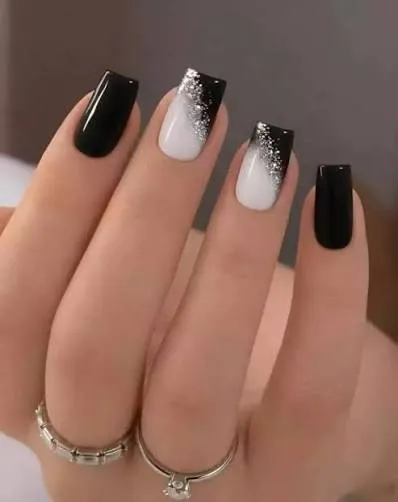 Black and white glitter gradient nails fading from glossy black to sparkling silver dust