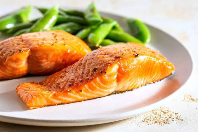 A cooked salmon fillet served with green vegetables on a plate