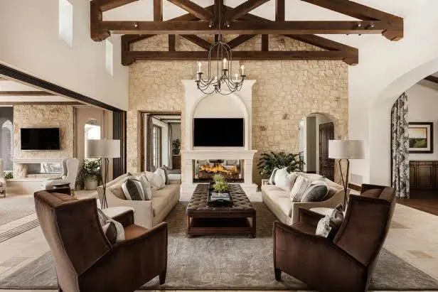 Warm, neutral farmhouse-style living room with stone fireplace, exposed wood beams, and welcoming seating