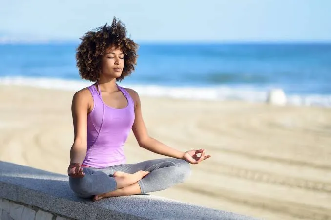 A woman practicing mindful meditation beside the ocean